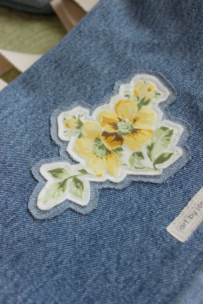 An up-close photo floral patch on a handmade denim bag