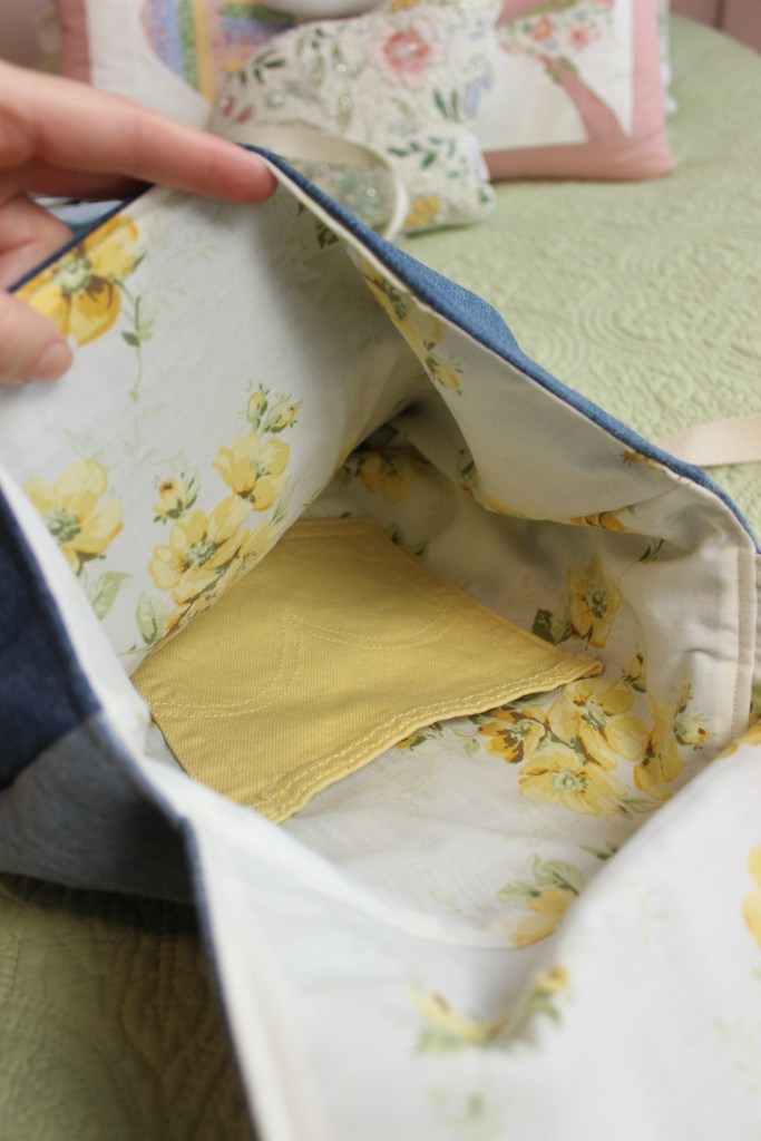 The inside of a denim bag, showing a floral design and an inner pocket
