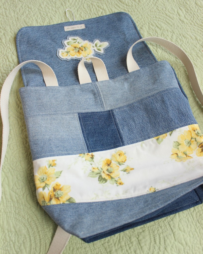 The details of a handmade denim bag with floral designs on it