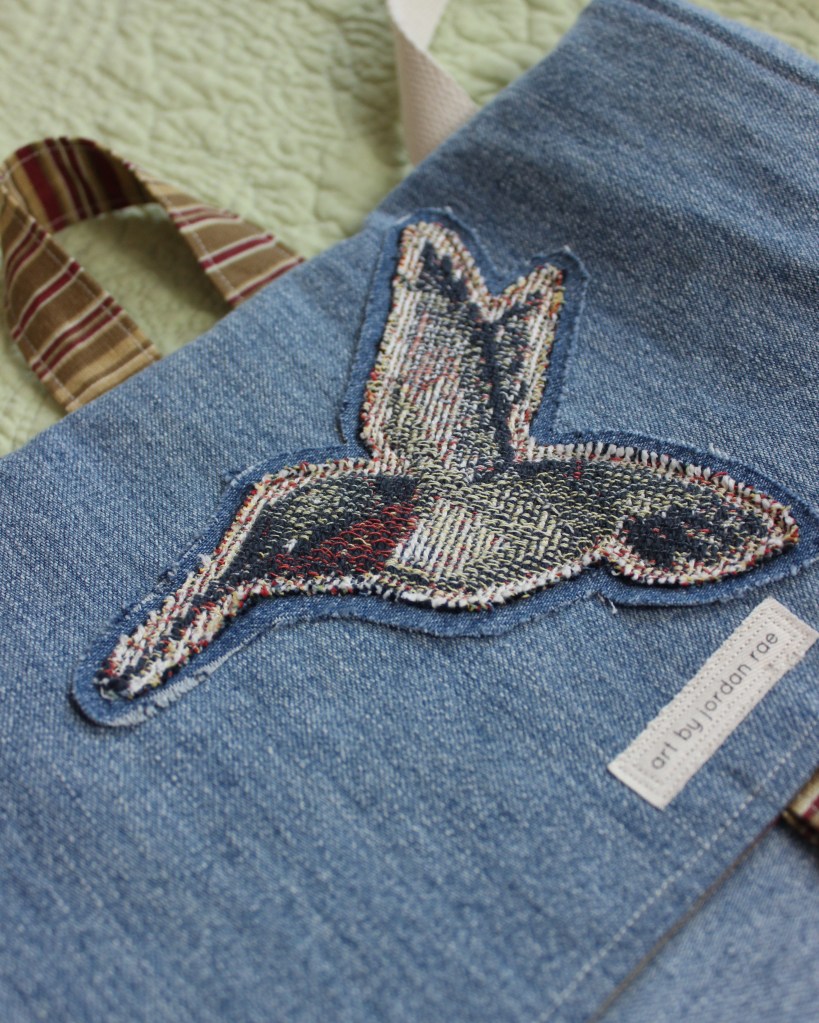 An up-close photo of a hummingbird patch on a handmade denim bag