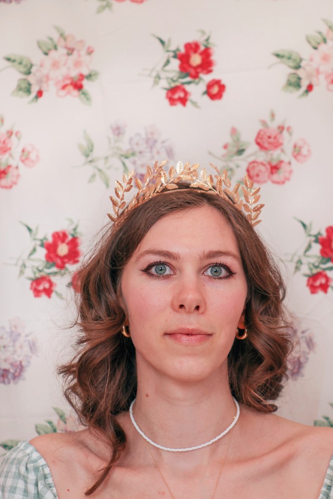 A girl sits with a floral backdrop behind her