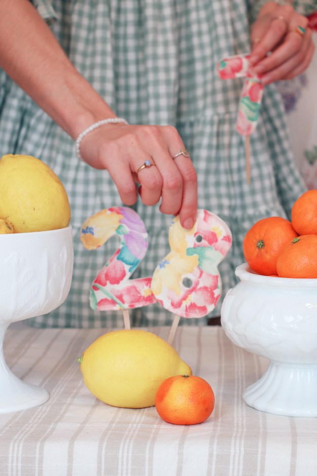 A hand reaches for the number "28" in between bowls of fruit.