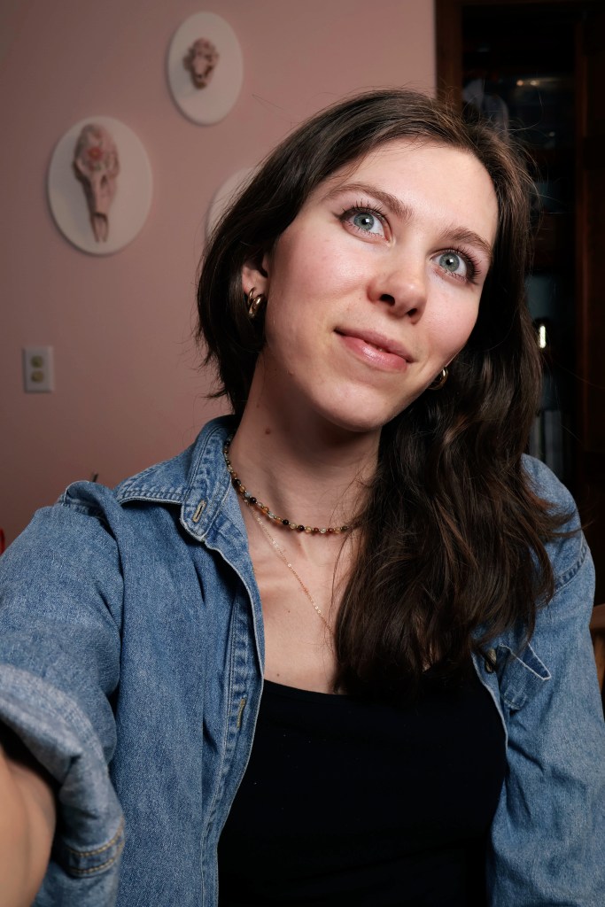 A girl wearing a blue shirt smiles and looks at the camera.