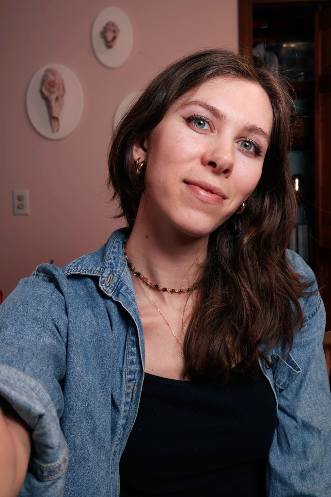 A girl wearing a blue shirt smiles and looks at the camera.